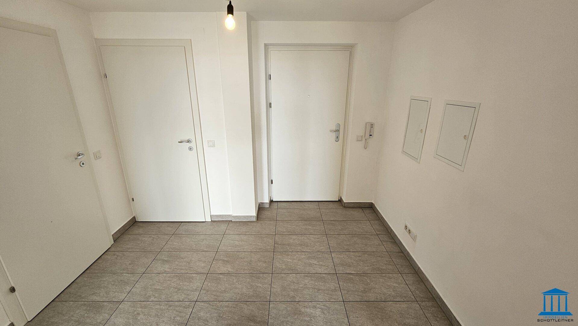 Heller Flur mit Fliesenboden und Zugang zur Wohnungstür sowie weiteren Räumen.