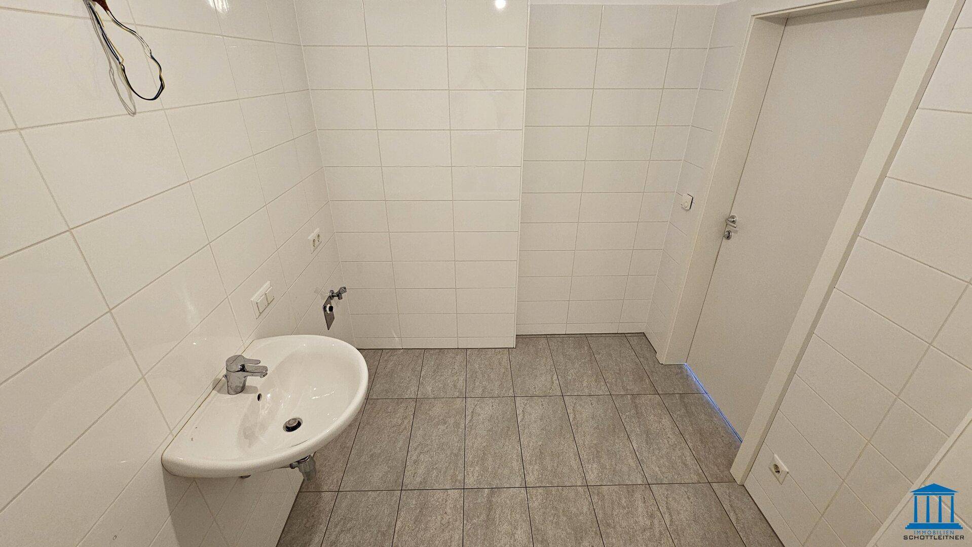 Modernes Badezimmer mit Waschbecken und weißen Fliesen, bietet ausreichend Platz.