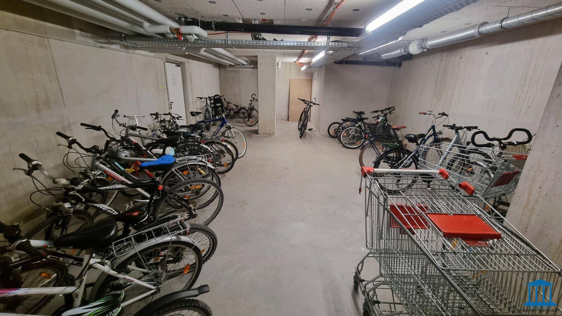 Fahrradraum im Untergeschoss mit vielen Fahrrädern und Einkaufswagen, praktisch für Bewohner.