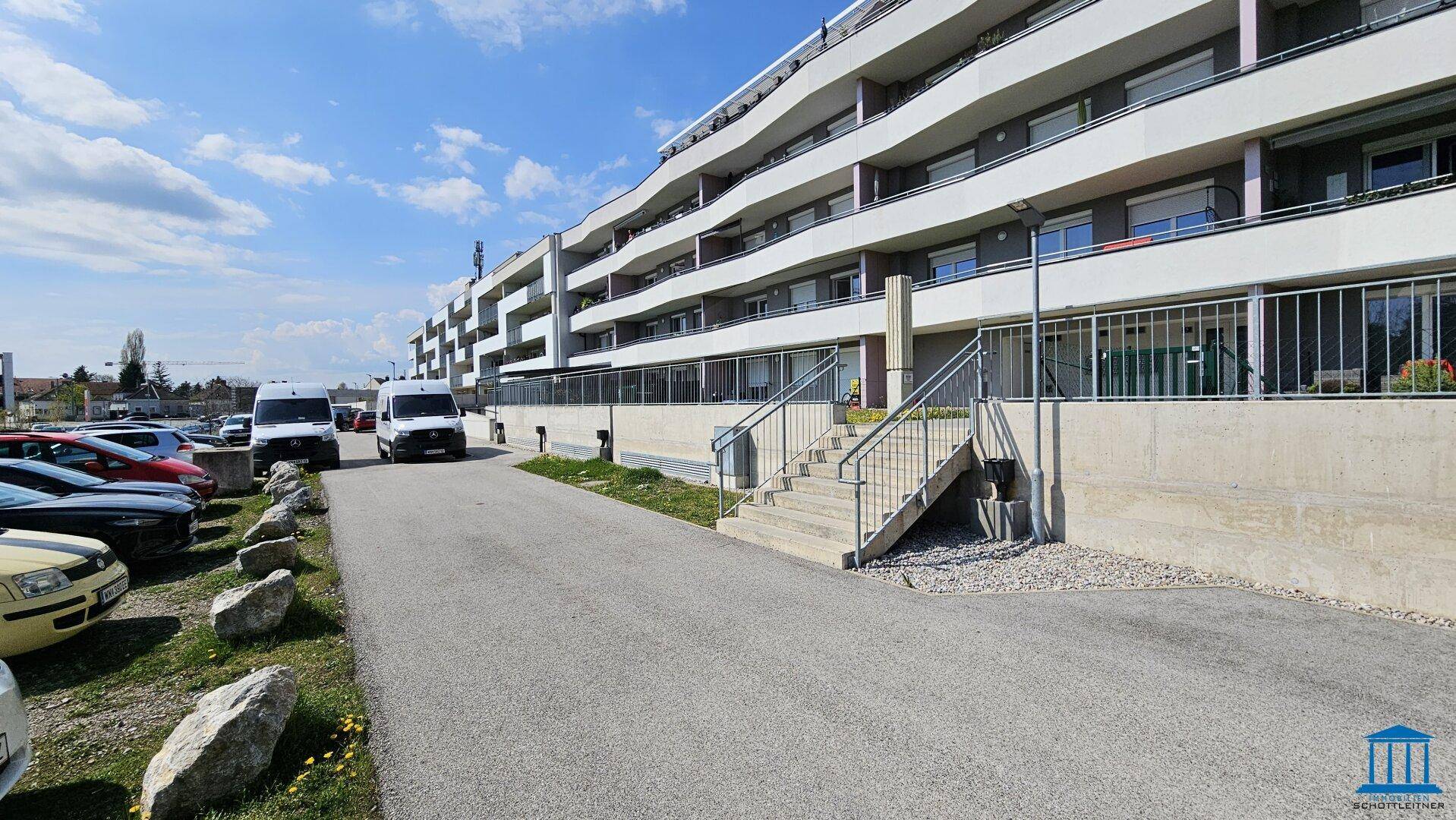 Moderne Wohnanlage mit mehreren Etagen, Balkonen und Außenparkplätzen.