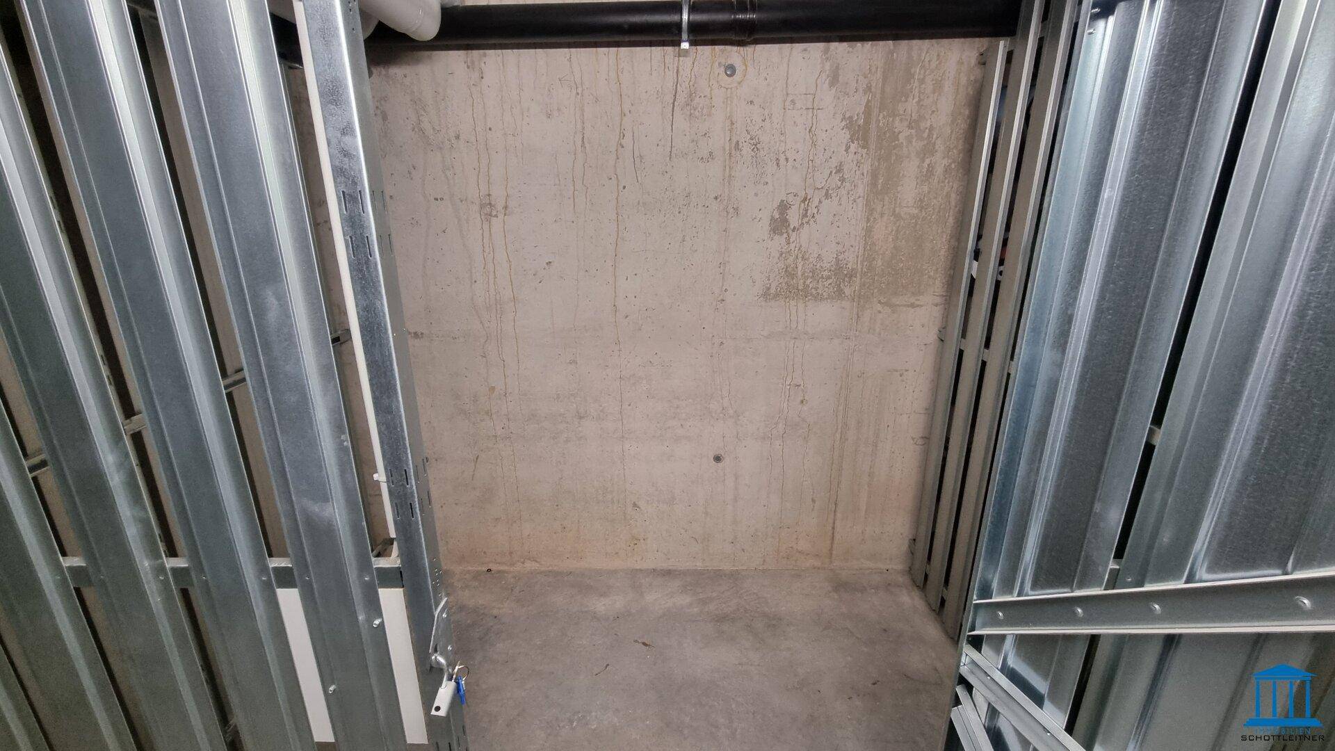 Abstellraum im Keller mit Metallabtrennungen und Betonwänden, ideal für zusätzlichen Stauraum.