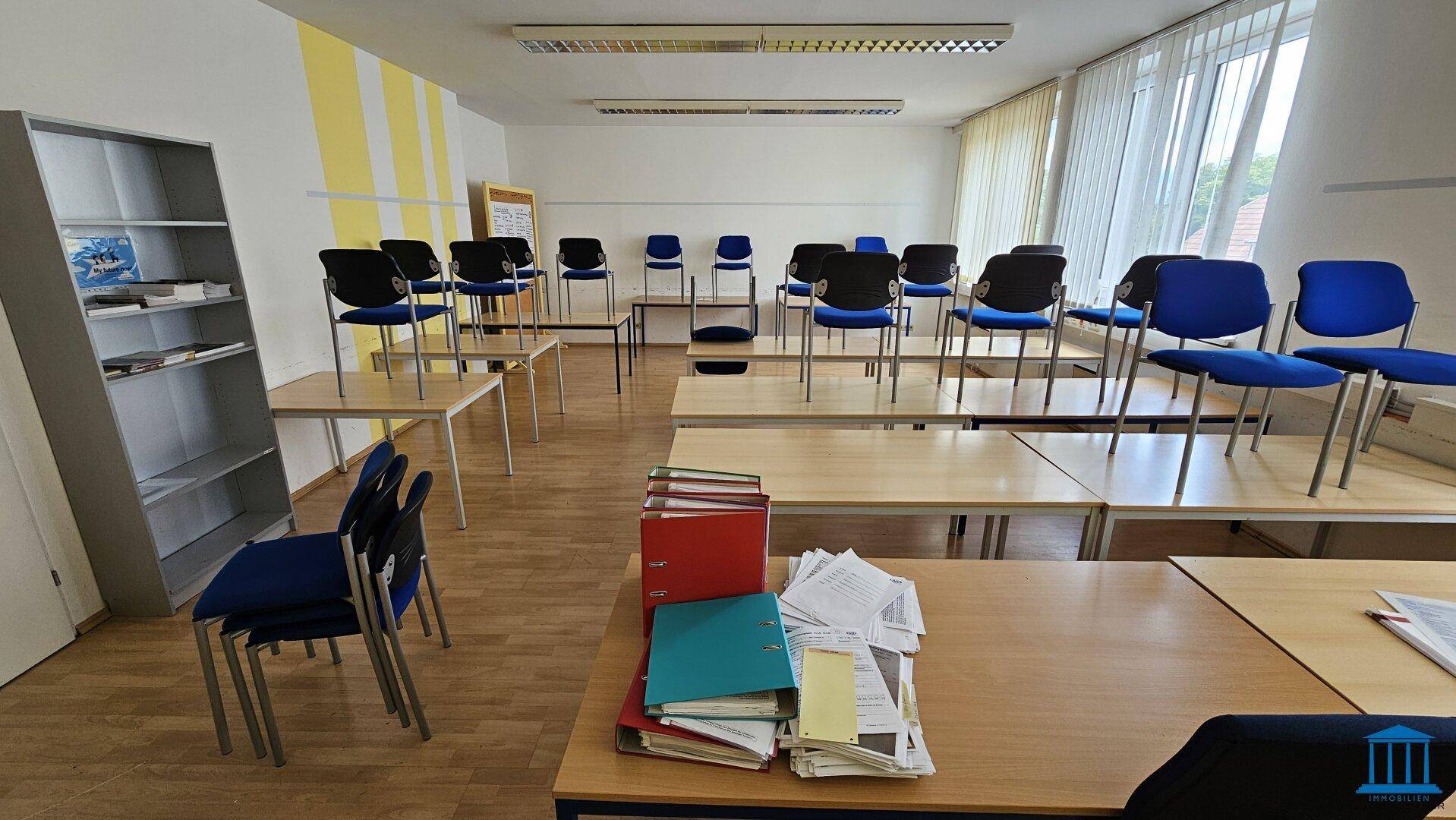 Heller Konferenzraum mit vielen Tischen und Stühlen, bereit für Seminare und Präsentationen.