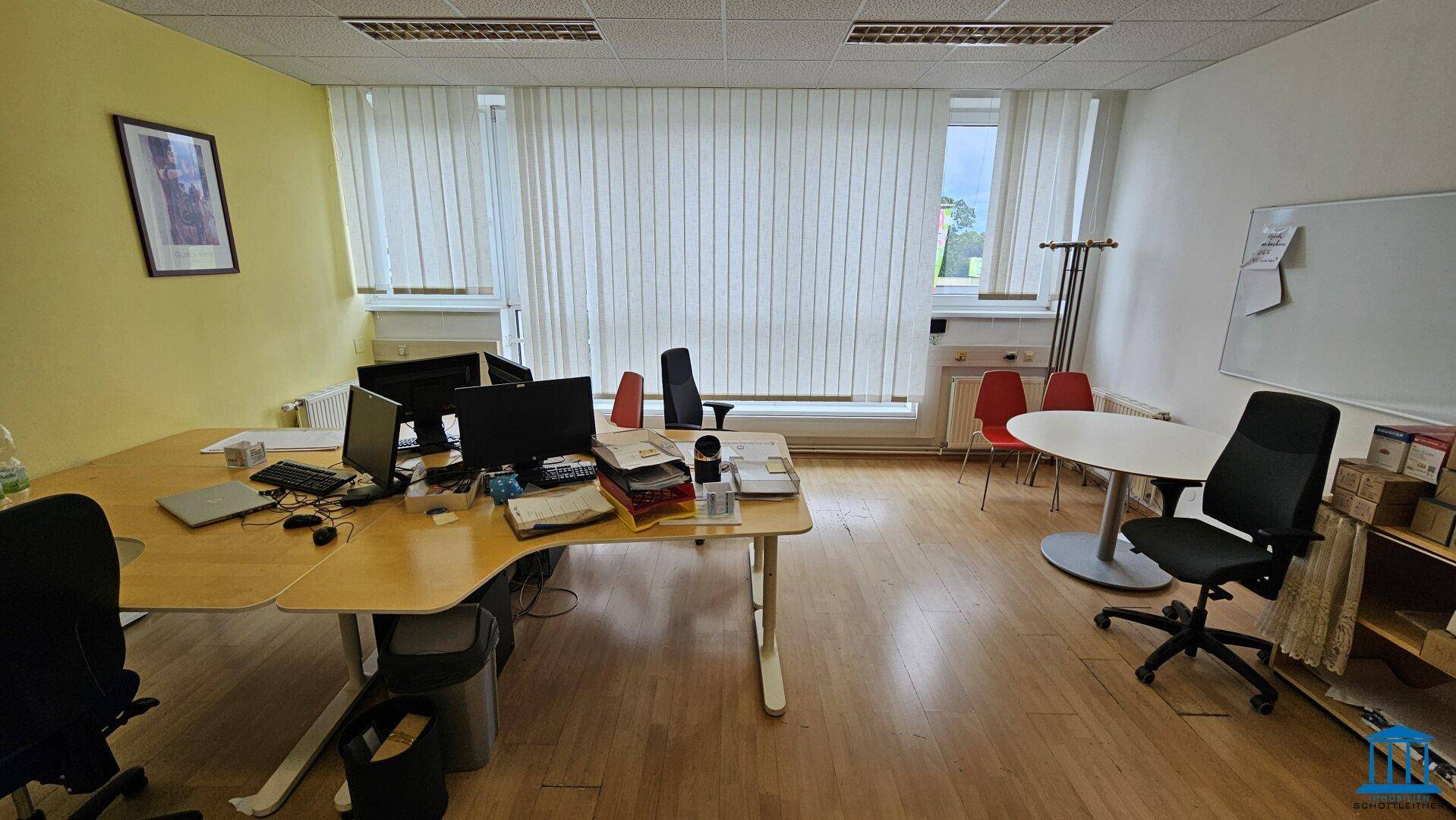 Helles Büro mit mehreren Arbeitsplätzen, Computern und einem Whiteboard, ideal für Teamarbeit.