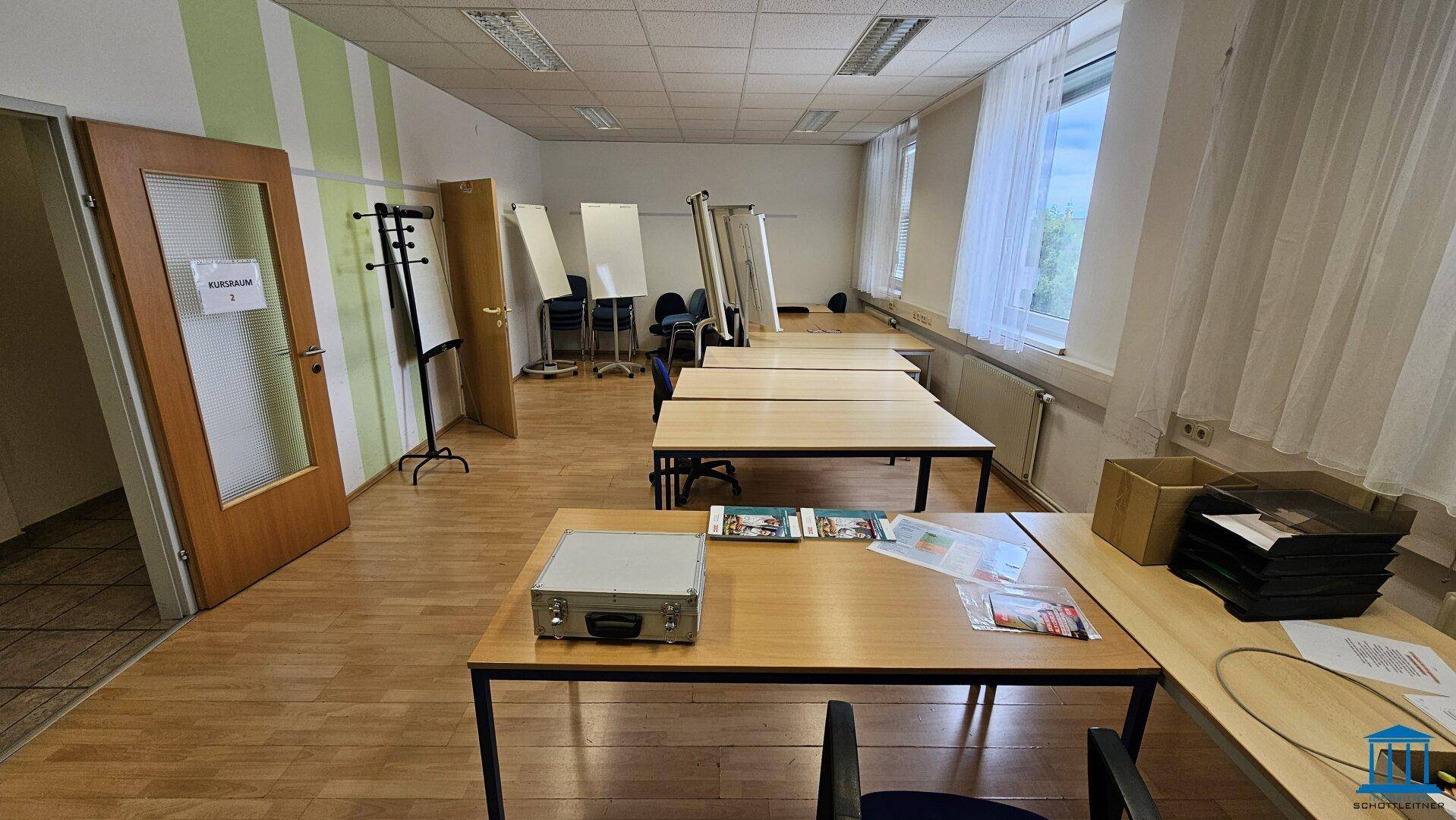 Schulungsraum mit Tischen, Stühlen und Flipcharts, bereit für Unterricht oder Workshops.