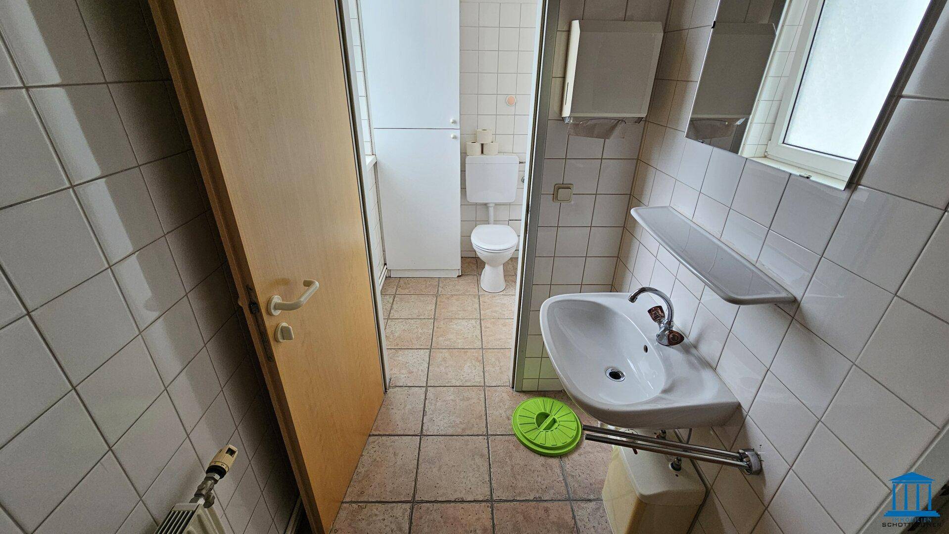 Kleines Badezimmer mit Waschbecken, Toilette und Fenster, einfach und funktional.