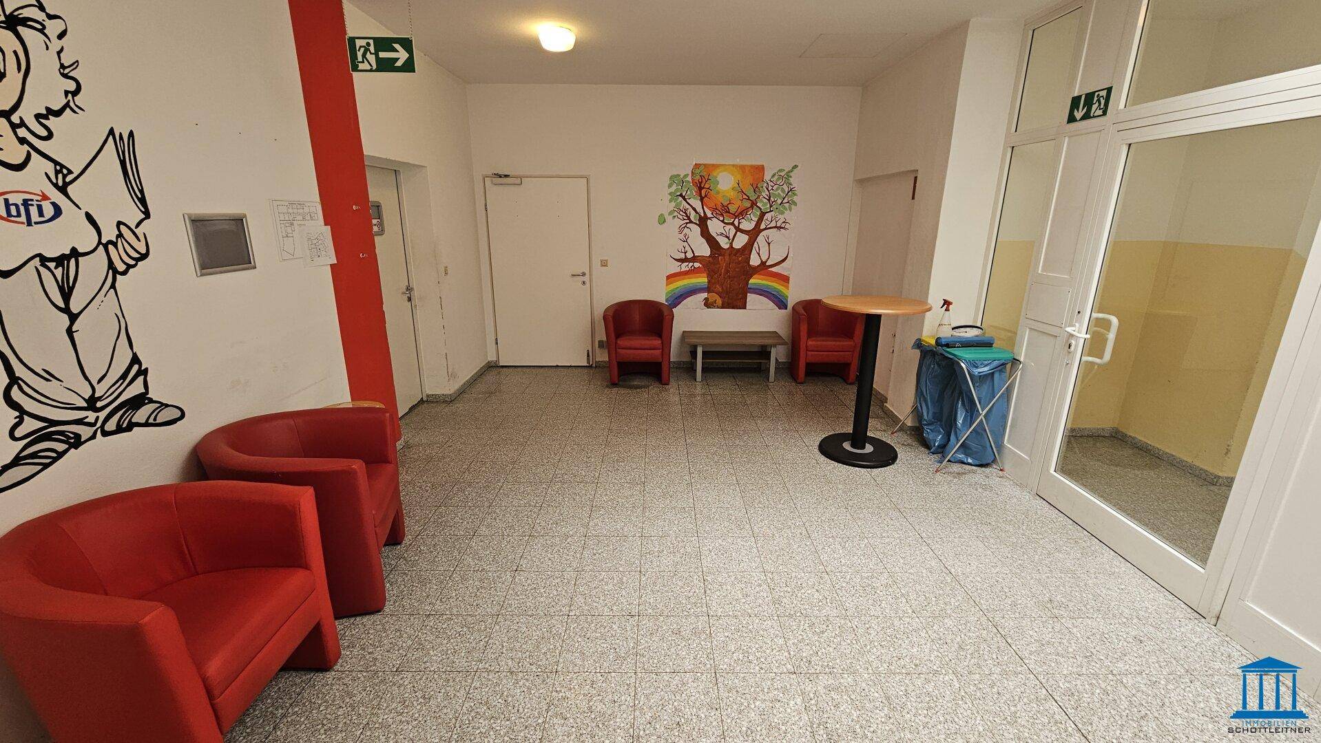Heller Eingangsbereich mit Sitzgelegenheiten und farbenfroher Wanddekoration, einladend gestaltet.