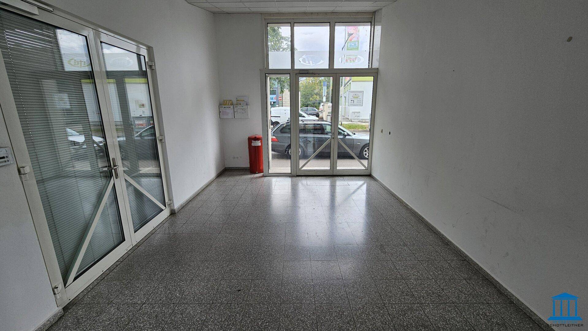 Leerer Ladenraum mit großen Glasfronten zur Straße, Fliesenboden und viel Tageslicht, ideal für Einzelhandel.