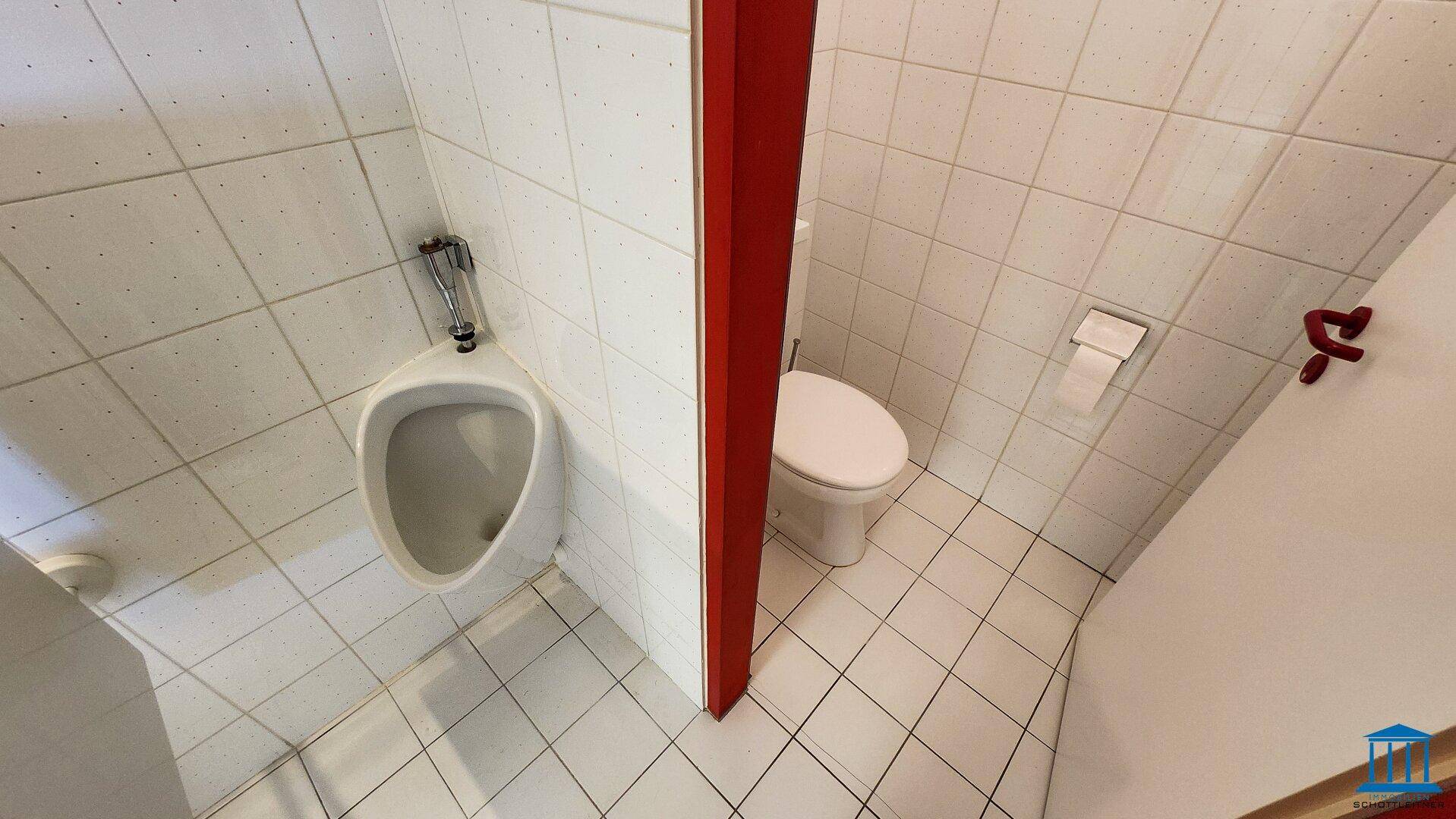 Herrentoilette mit Urinal, WC und weißen Fliesen an Wänden und Boden, sehr sauber.