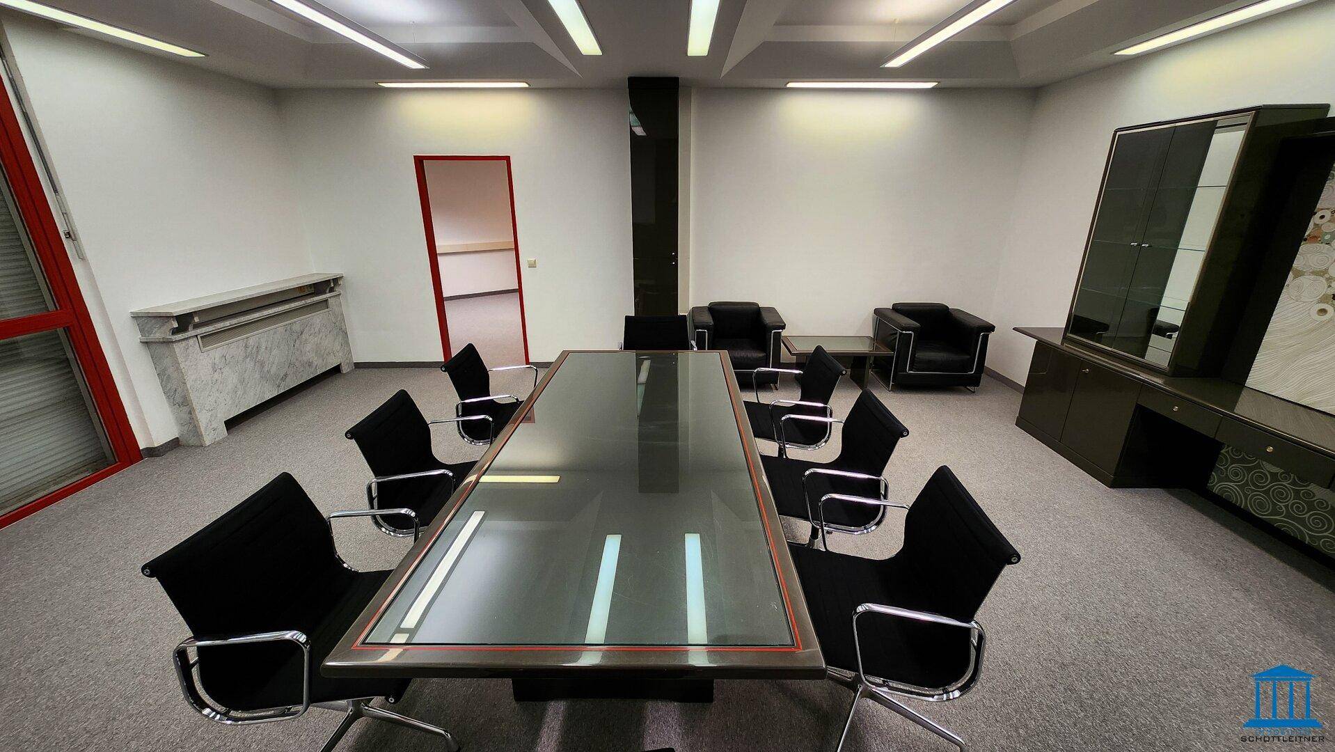Konferenzraum mit großem Glastisch, schwarzen Stühlen und Teppichboden, elegant eingerichtet.