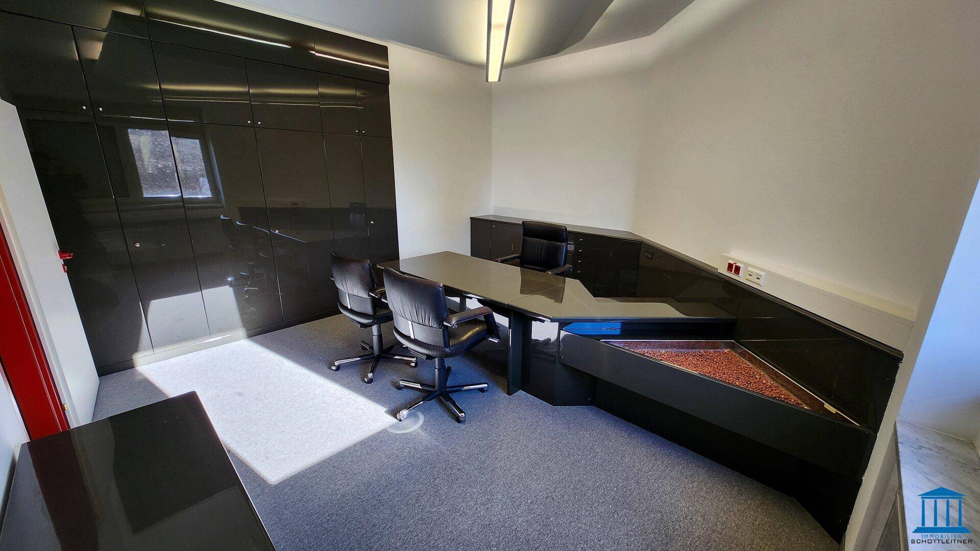 Elegantes Büro mit schwarzem Schreibtisch, Büroschränken und Teppichboden in dunklem Grau.