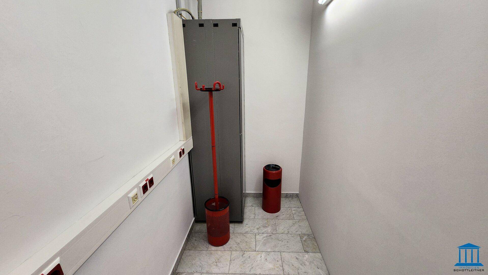 Schmaler Flur mit Fliesenboden und roten Abfalleimern, sauber und funktional gestaltet.