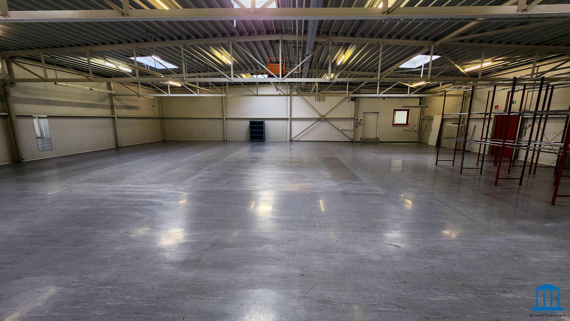 Geräumige Lagerhalle mit Betonboden und Metallregalen, bereit für die Nutzung und Organisation.