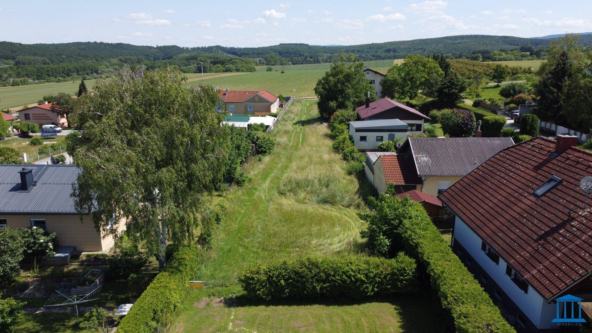 Luftaufnahme eines weitläufigen, grünen Grundstücks umgeben von Wohnhäusern und ländlicher Landschaft.