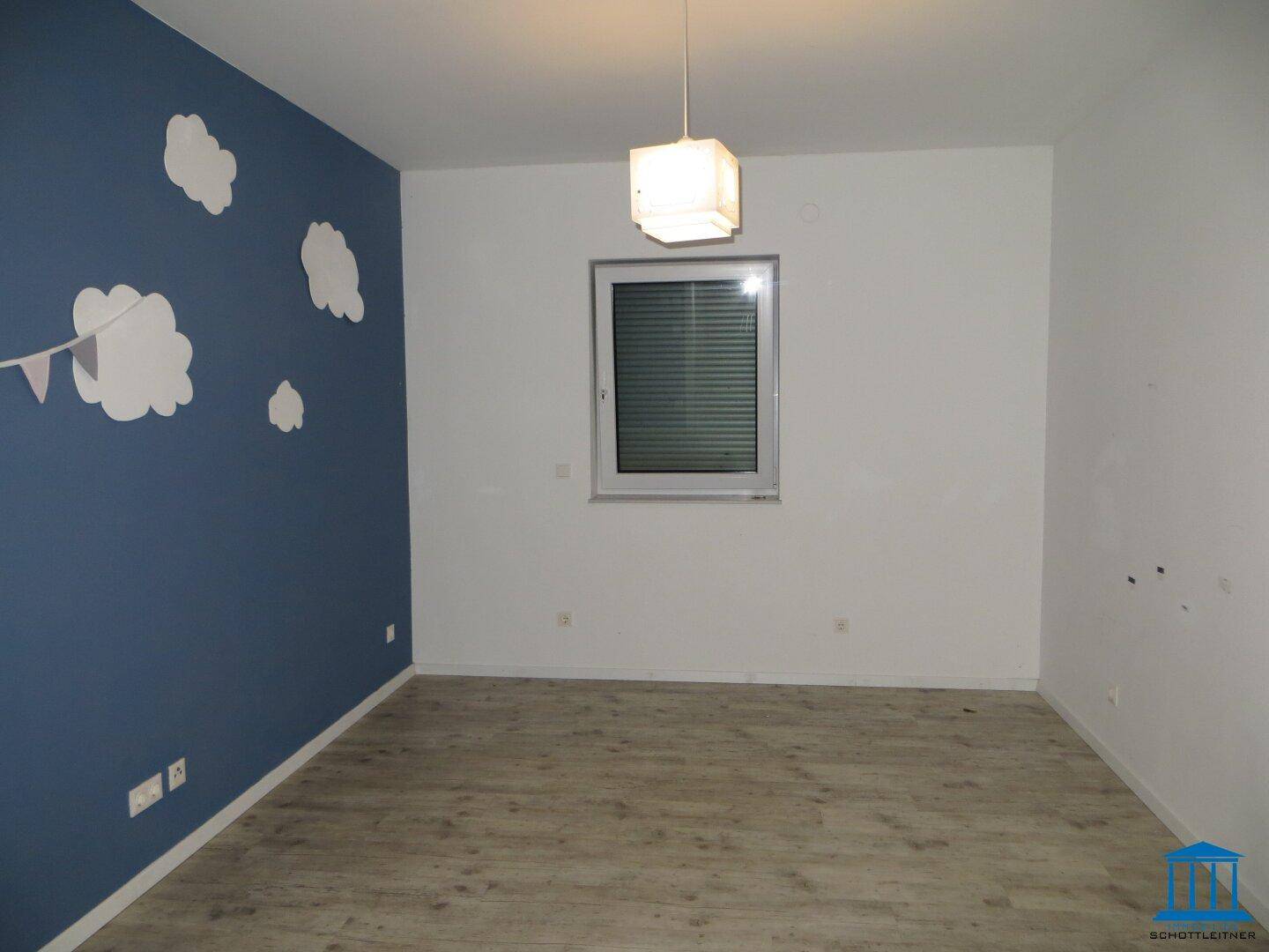 Kinderzimmer mit blauer Akzentwand und Laminatboden.