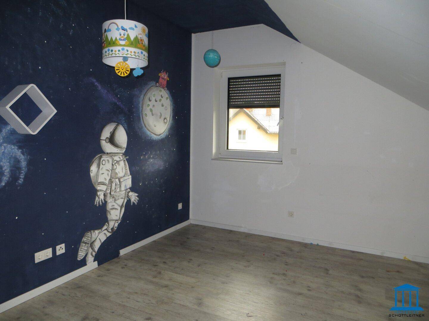Kinderzimmer im Dachgeschoss mit Weltraum-Wandmalerei und Schrägdach.