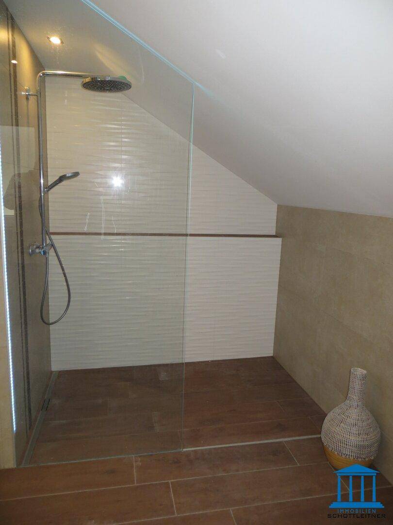 Begehbare Dusche mit Glaswand und Regenduschkopf im modernen Badezimmer.
