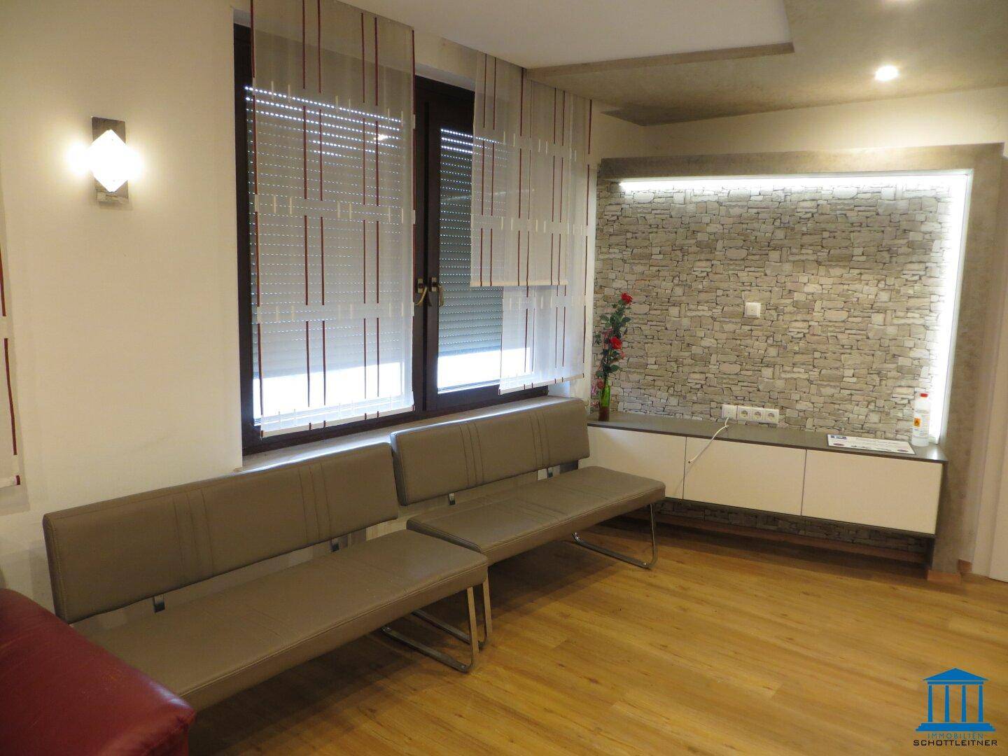 Wohnzimmer mit Steinwand-Akzent, Holzboden und modernen Bänken.