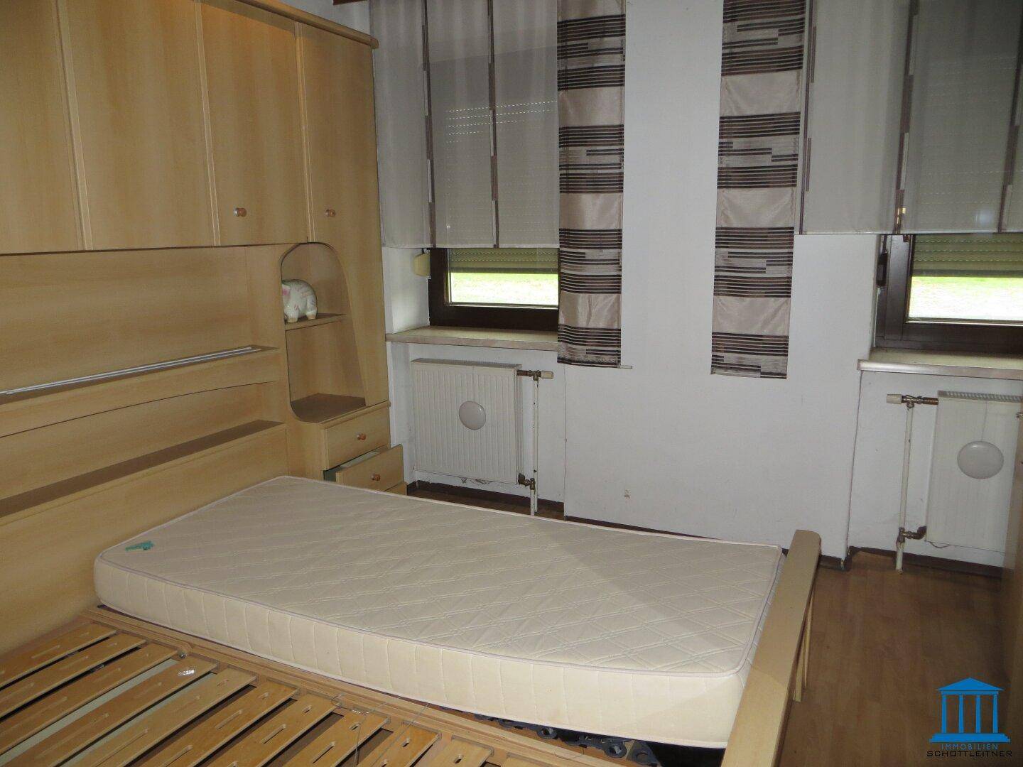Schlafzimmer mit Holzbett, Einbauschränken und Laminatboden.