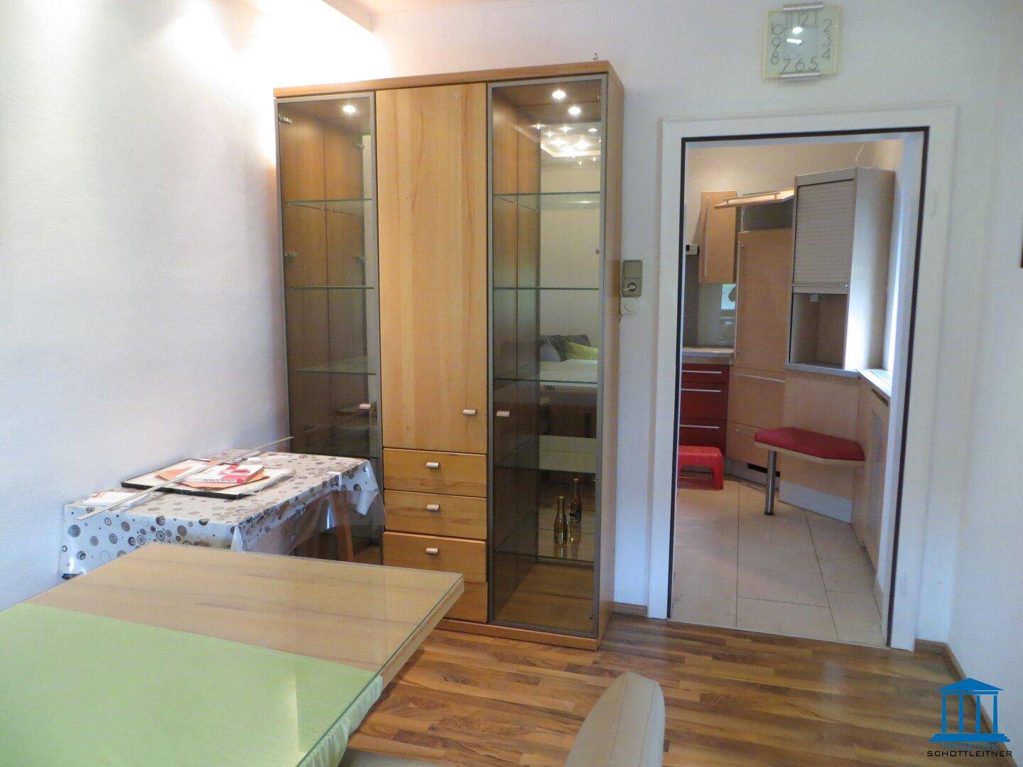 Esszimmer mit Vitrinenschrank, Holztisch und Zugang zur Küche.