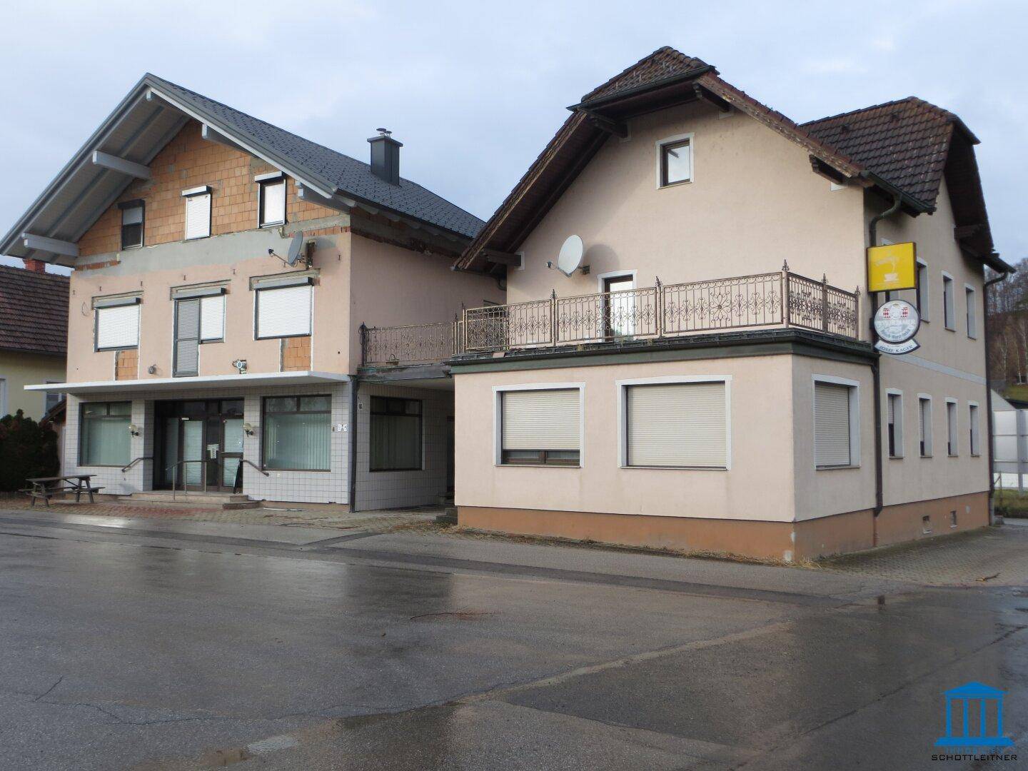 Seitenansicht des Gebäudes mit teilweise verputzter Fassade und Balkon.