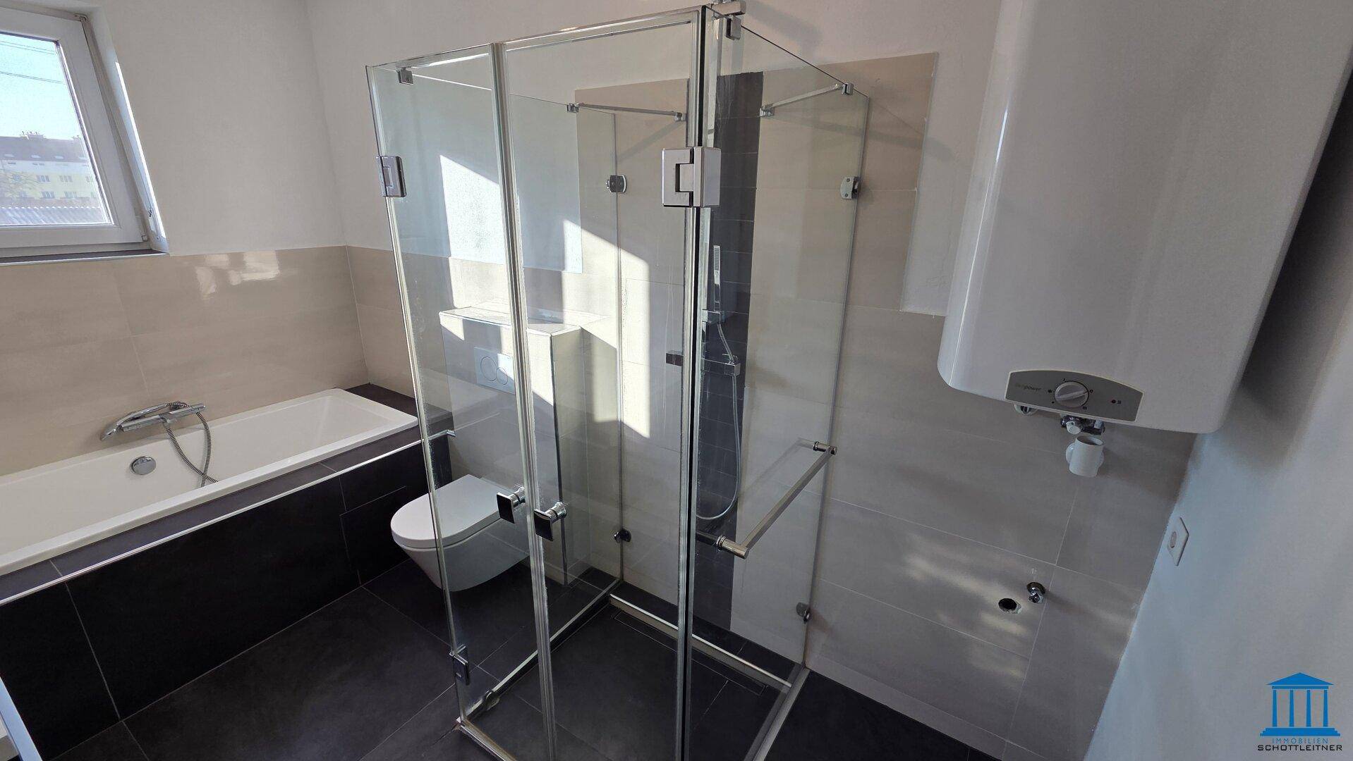 Badezimmer mit moderner Glasdusche, Badewanne und einem Fenster, das den Raum erhellt.