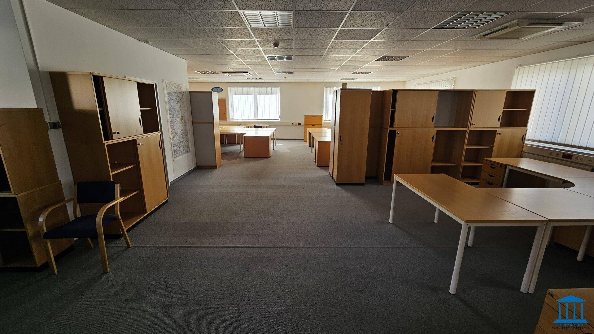 Geräumiges Büro mit Teppichboden und zahlreichen Holzschränken, die viel Stauraum bieten.