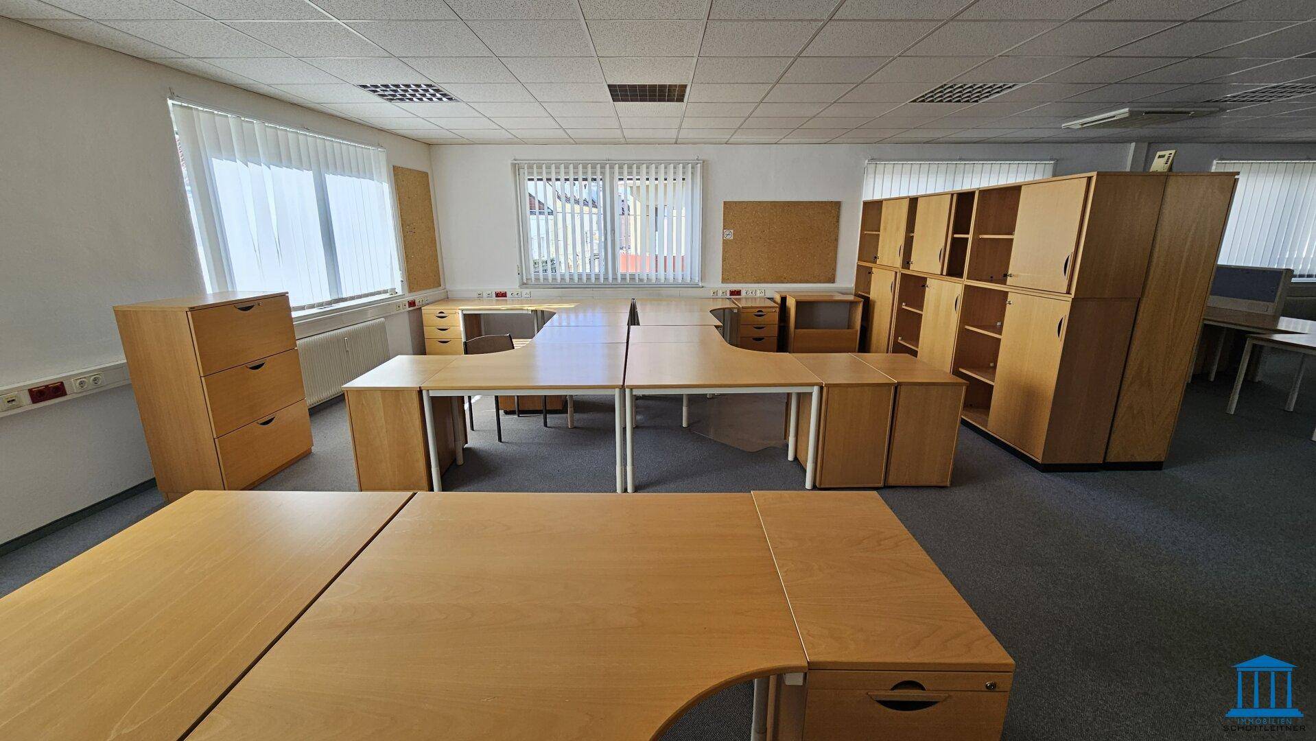 Helles Büro mit mehreren Schreibtischen und Holzschränken, ideal für ein Team.