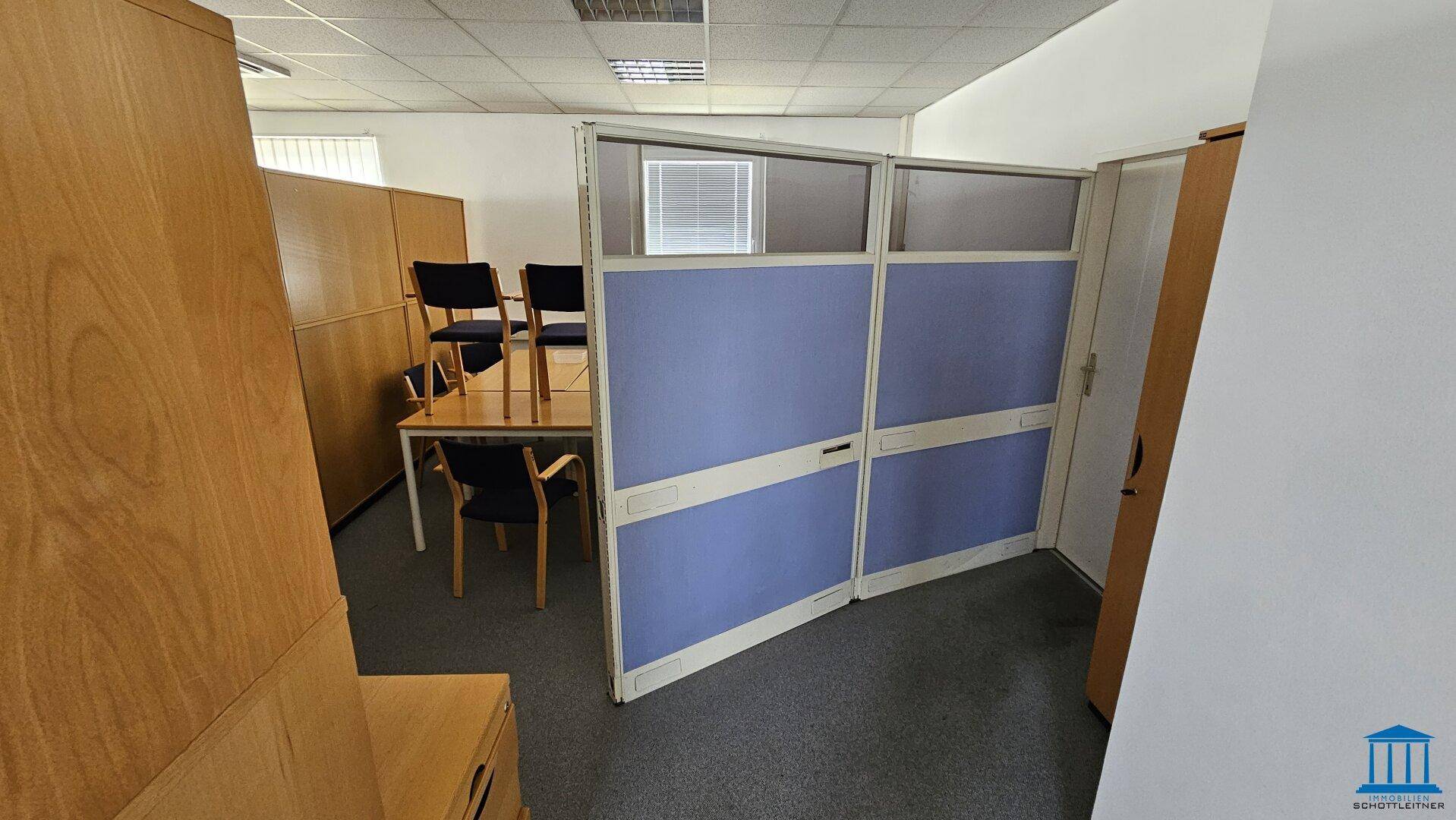Abgetrennter Bürobereich mit Trennwänden und einem Tisch mit Stühlen, ideal für Besprechungen.