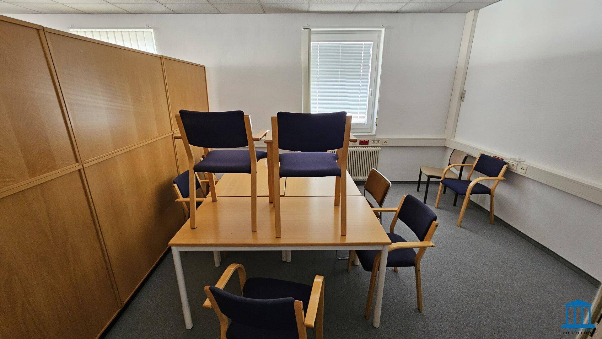 Kleinerer Bürobereich mit einem Tisch und mehreren Stühlen, ideal für Besprechungen oder Pausen.