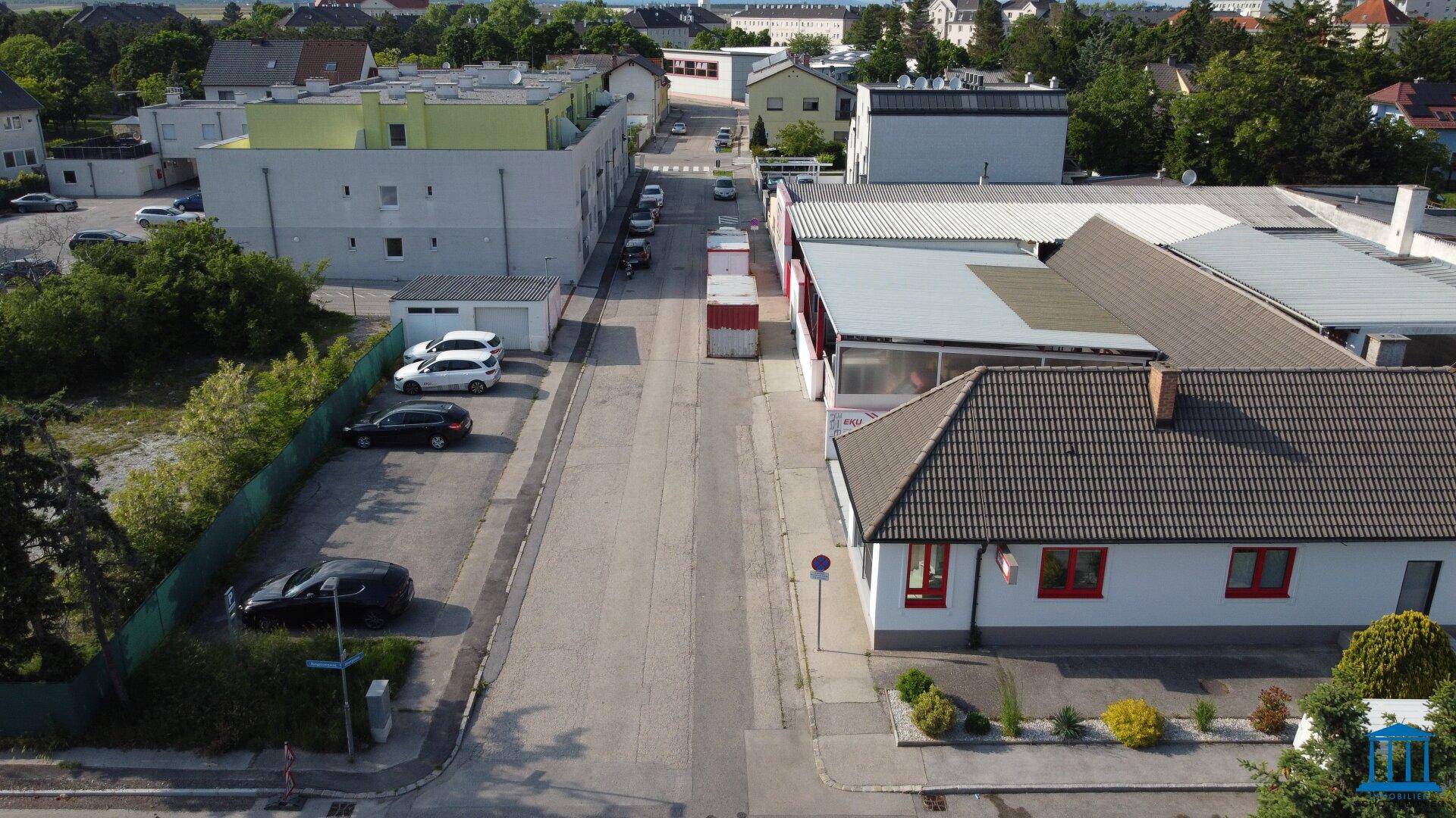 Luftaufnahme einer ruhigen Straße neben dem Gewerbeobjekt, gesäumt von Wohnhäusern und geparkten Autos.