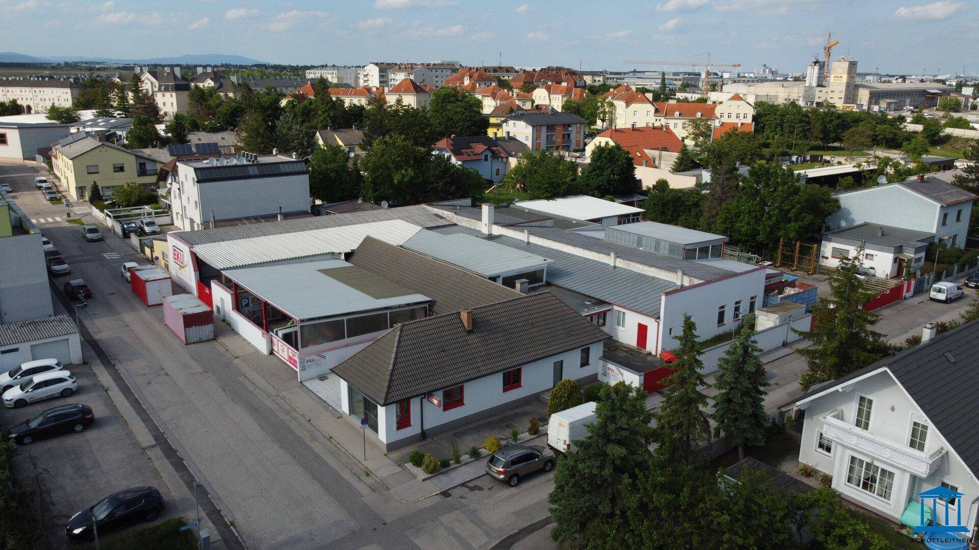 Weitläufige Luftansicht des Gewerbekomplexes, umgeben von Bäumen und Wohnhäusern, mit klarer Sicht auf die Umgebung.