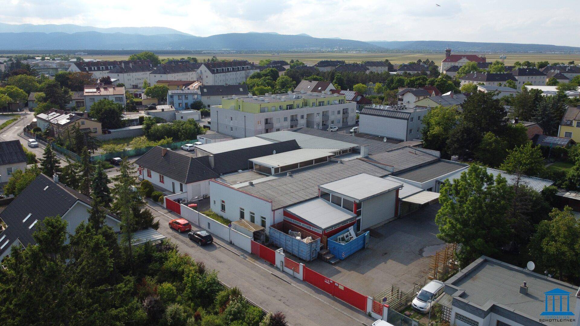 Weitwinkel-Luftaufnahme des Gewerbeareals mit Blick auf die Rückseite der Gebäude und eine ferne Bergkette.