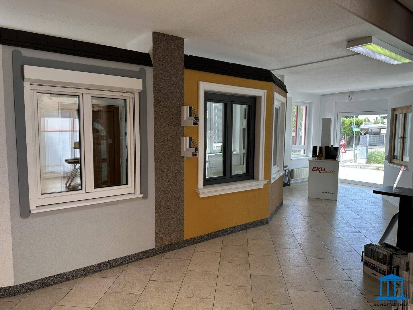 Ausstellungsraum mit verschiedenen Fenstermodellen und Rollläden, präsentiert auf einem hellen Fliesenboden.