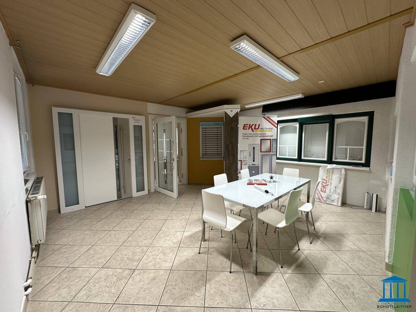 Besprechungsbereich im Ausstellungsraum mit modernem Tisch und Stühlen, umgeben von Produktmustern und Displays.
