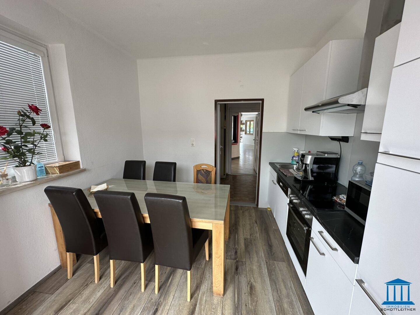 Moderne Küche mit weißen Schränken, dunkler Arbeitsplatte und Essbereich, ausgestattet mit Laminatboden.
