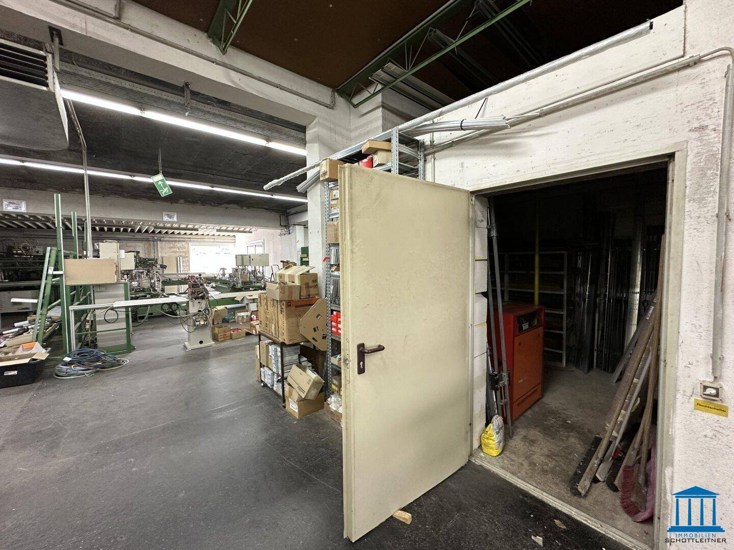 Eingangsbereich zu einem Werkstattraum mit einer offenen Tür und Lagerung von Materialien.