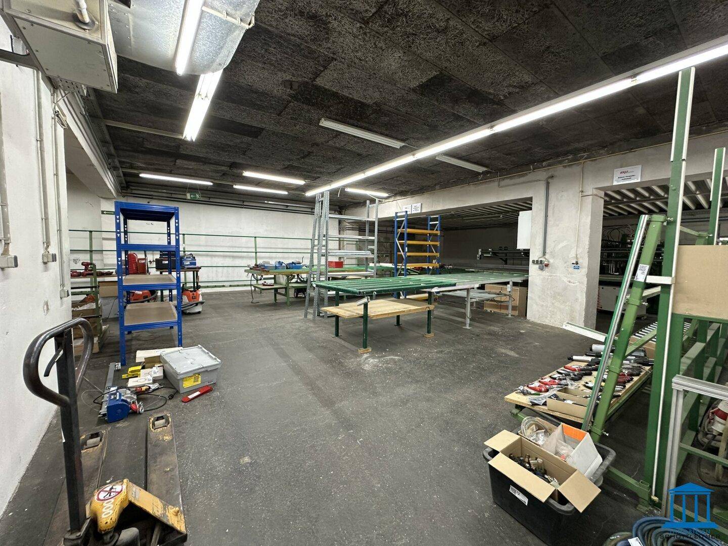 Große Werkstatt mit Regalen, Arbeitstischen und industrieller Ausstattung für verschiedene Arbeiten.