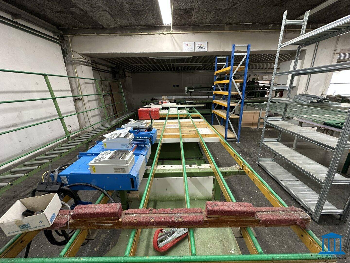 Industrielle Werkstatt mit Förderbändern, Maschinen und Regalen, bereit für Produktionsprozesse.