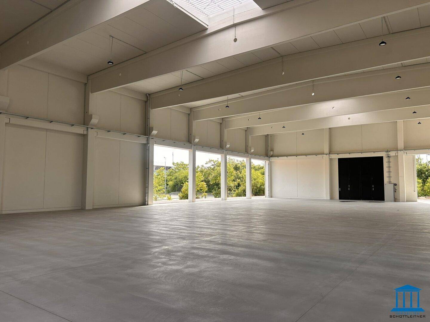 Geräumige Lagerhalle mit viel Tageslicht durch Oberlichter und große Öffnungen.