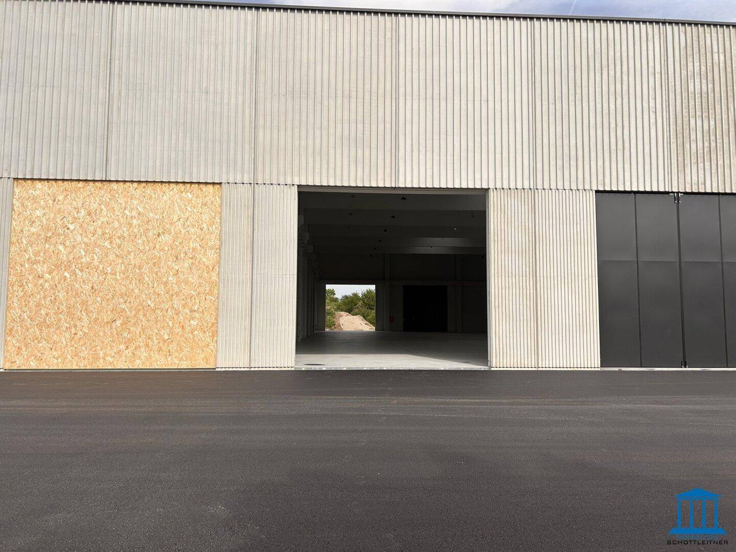Große Einfahrt zu einer Lagerhalle mit einer provisorisch verschlossenen Öffnung.