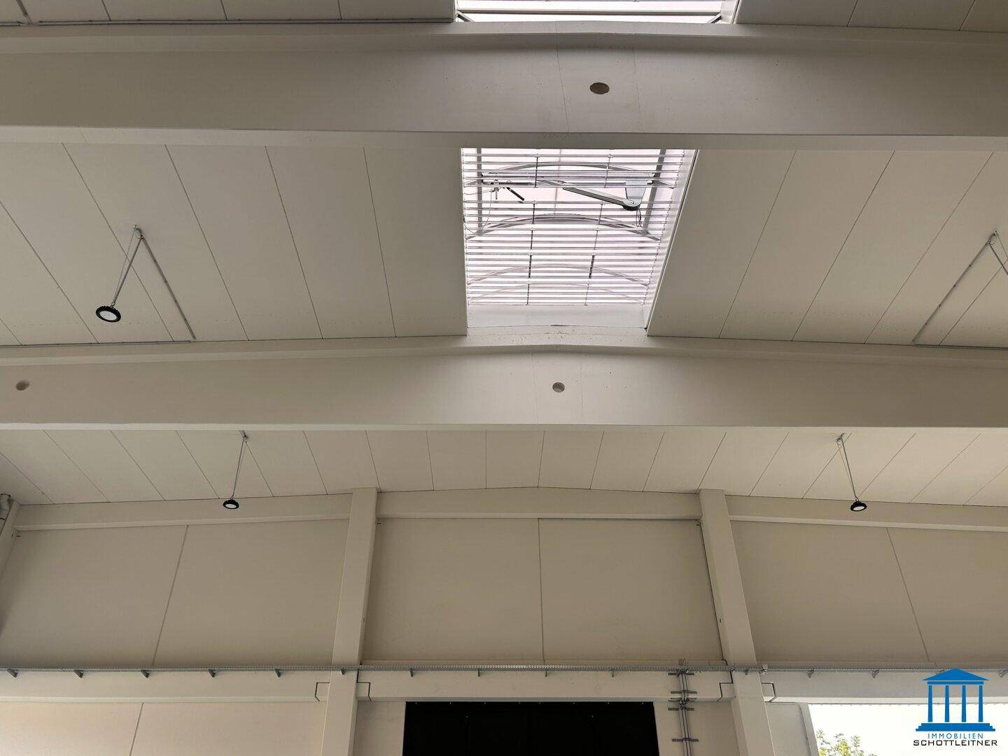 Hohe Decke einer Lagerhalle mit Oberlichtern und Beleuchtungselementen.