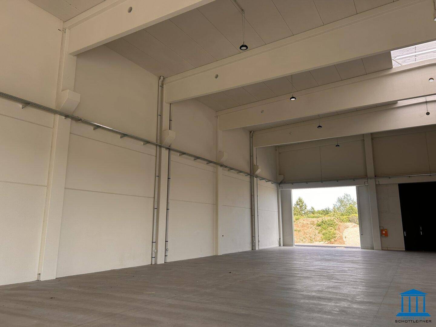 Innenansicht einer modernen Lagerhalle mit hohen Wänden und sichtbaren Installationen.