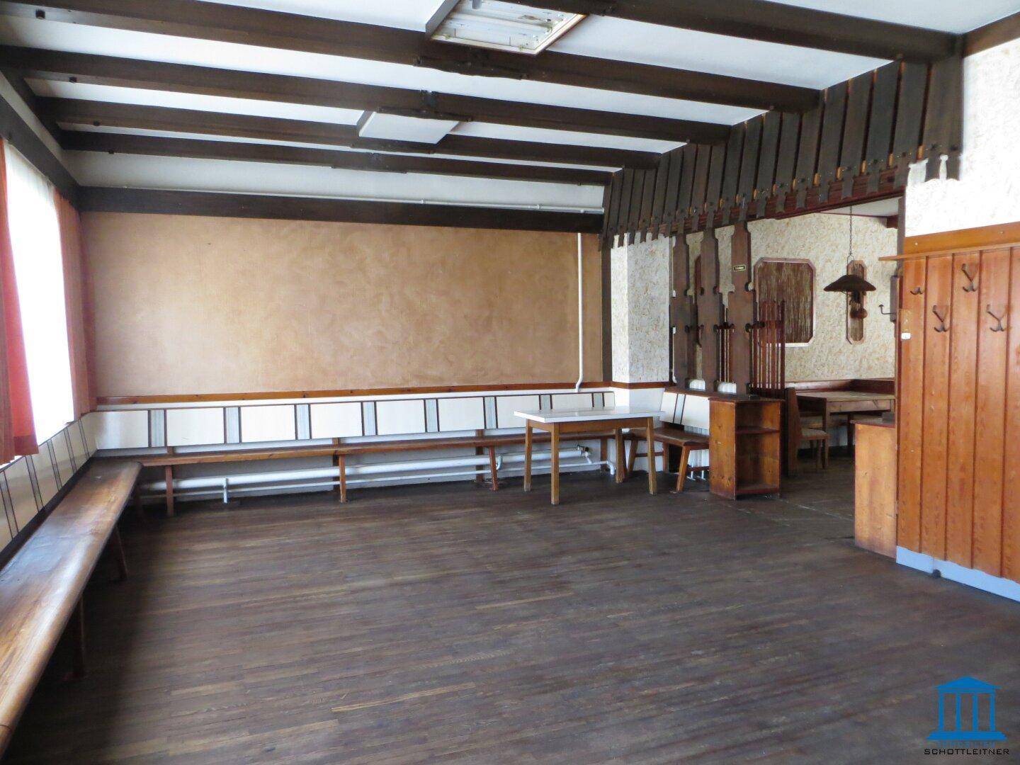Großer Raum mit Holzbalkendecke, Holzbänken und dunklem Holzboden im traditionellen Stil.