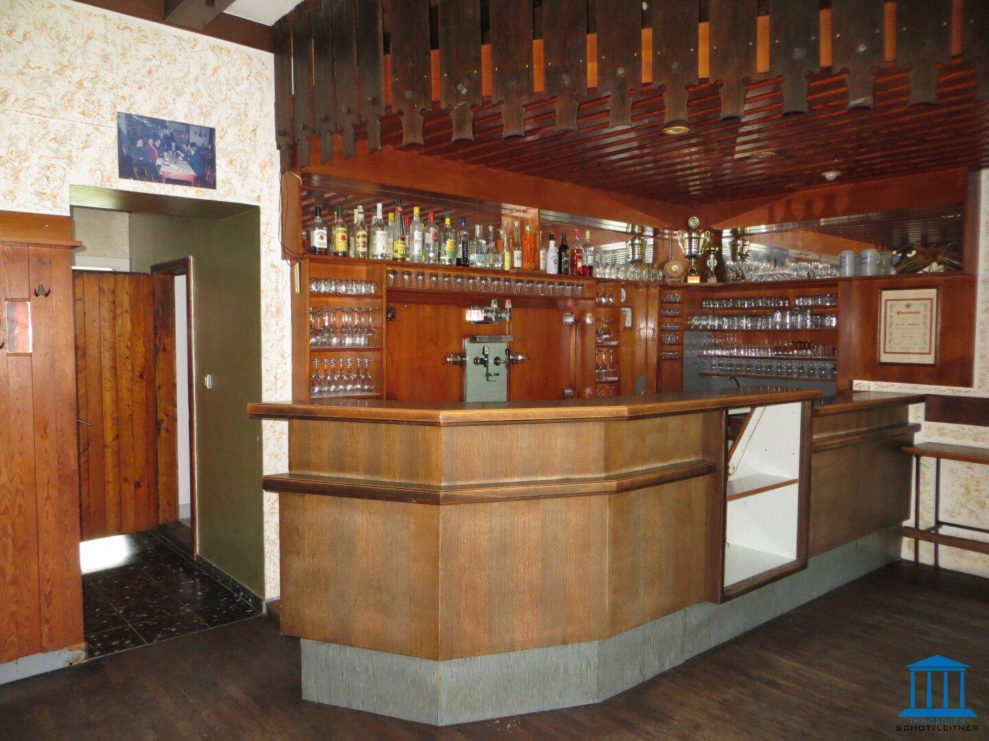 Traditionelle Holzbar mit Flaschenregalen, Gläsern und Zapfanlage.