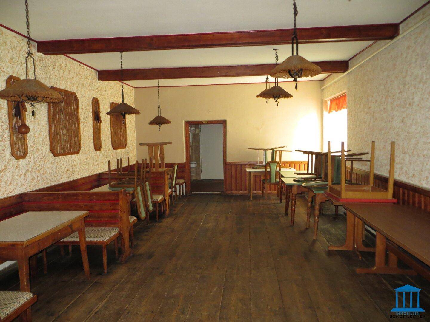 Rustikaler Speisesaal mit Holztischen, Bänken und traditionellen Hängelampen.