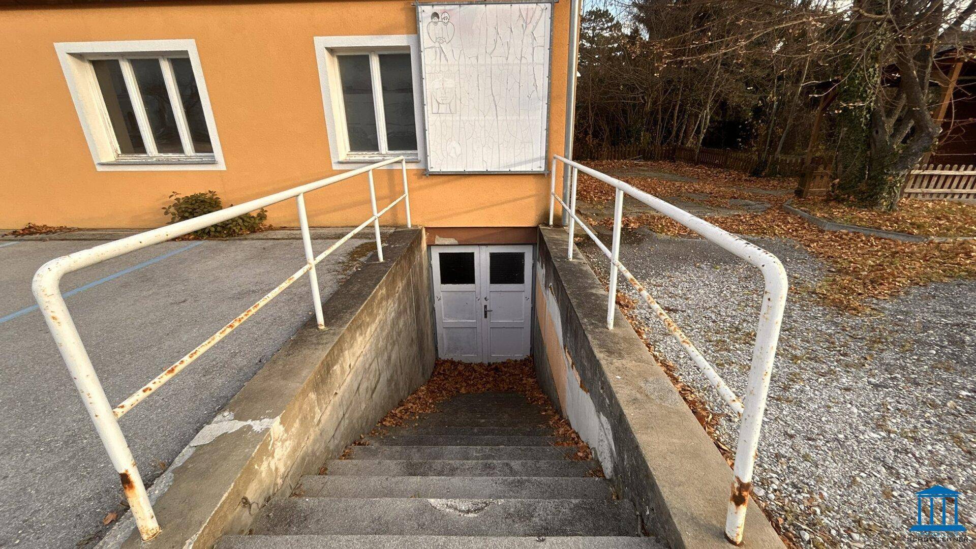 Treppe mit Geländer, die zu einem Kellereingang des Gebäudes führt.