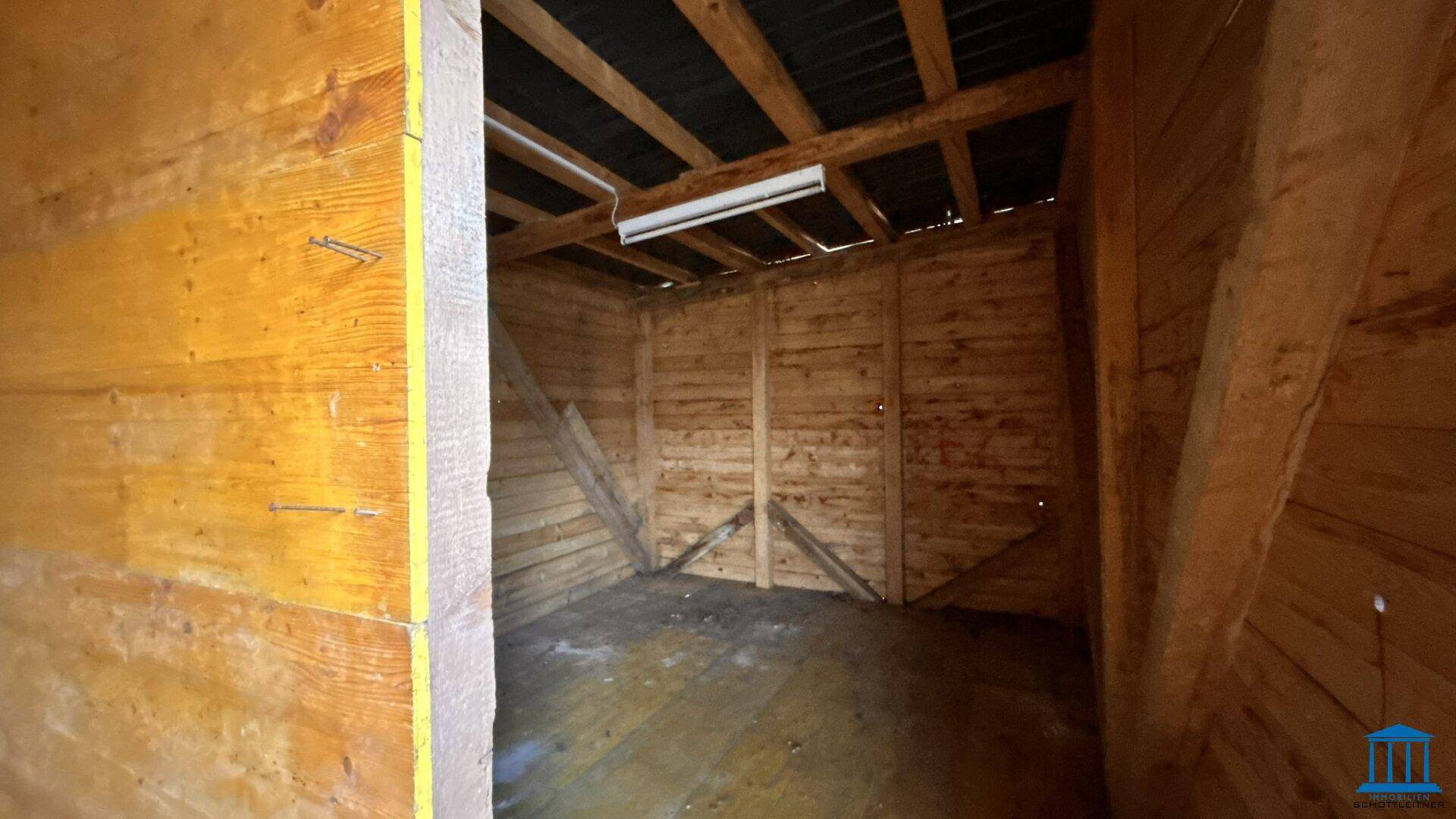 Innenansicht eines Holzschuppens mit sichtbaren Dachbalken und Holzverkleidung.