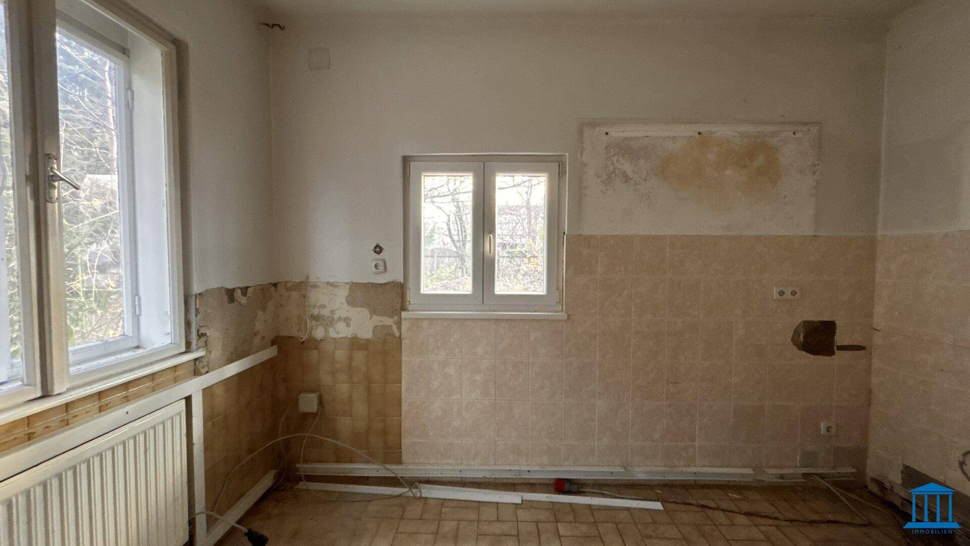 Raum mit teilweise gefliesten Wänden und einem Fenster, der auf eine Renovierung wartet.