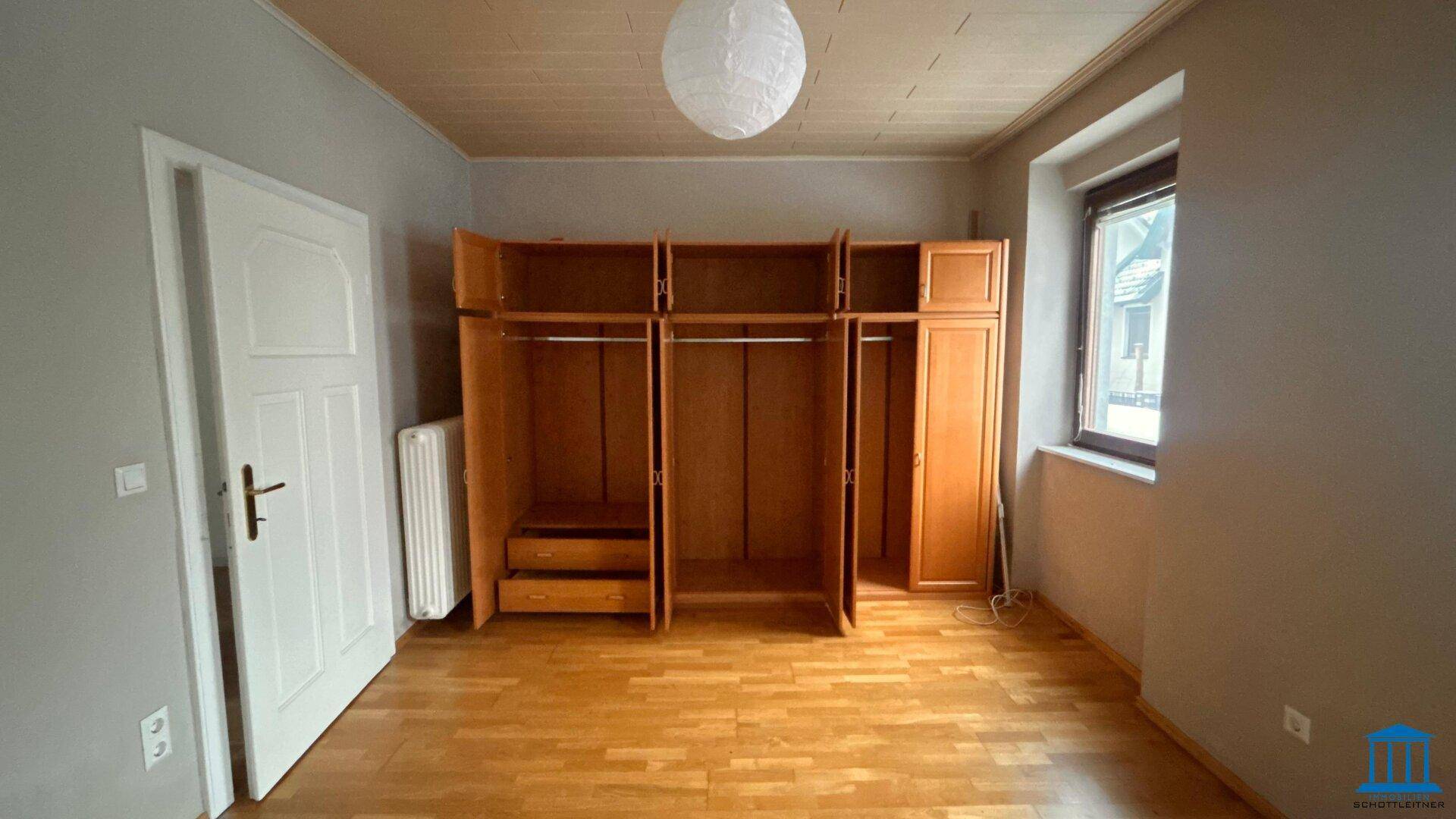 Schlafzimmer mit Holzboden, Holzdecke und einem offenen Kleiderschrank.