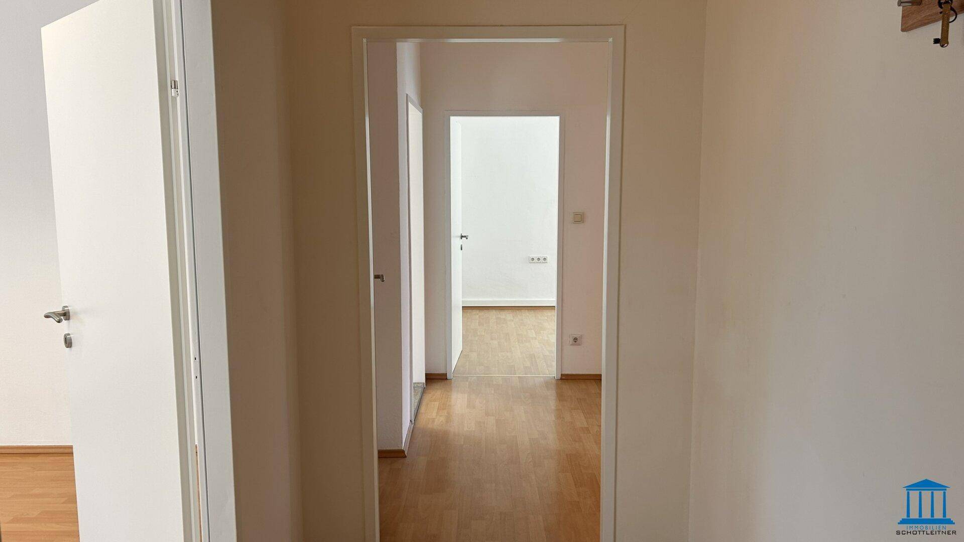 Langer Flur mit Holzboden und Türen, die zu weiteren Räumen führen.